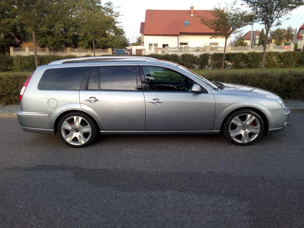 Stříbrný Ford Mondeo kombi z boku s tmavými zadními bočními skly